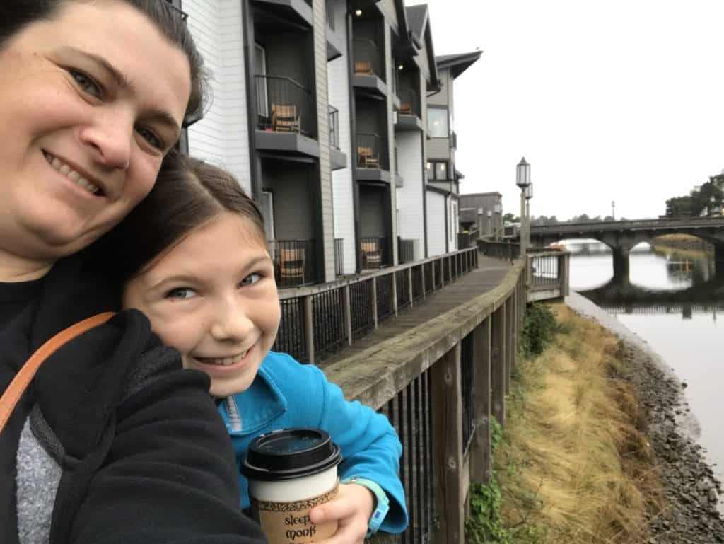 girl and mom with coffee cups along boardwalk of Necanicum river in Seaside, oregon.