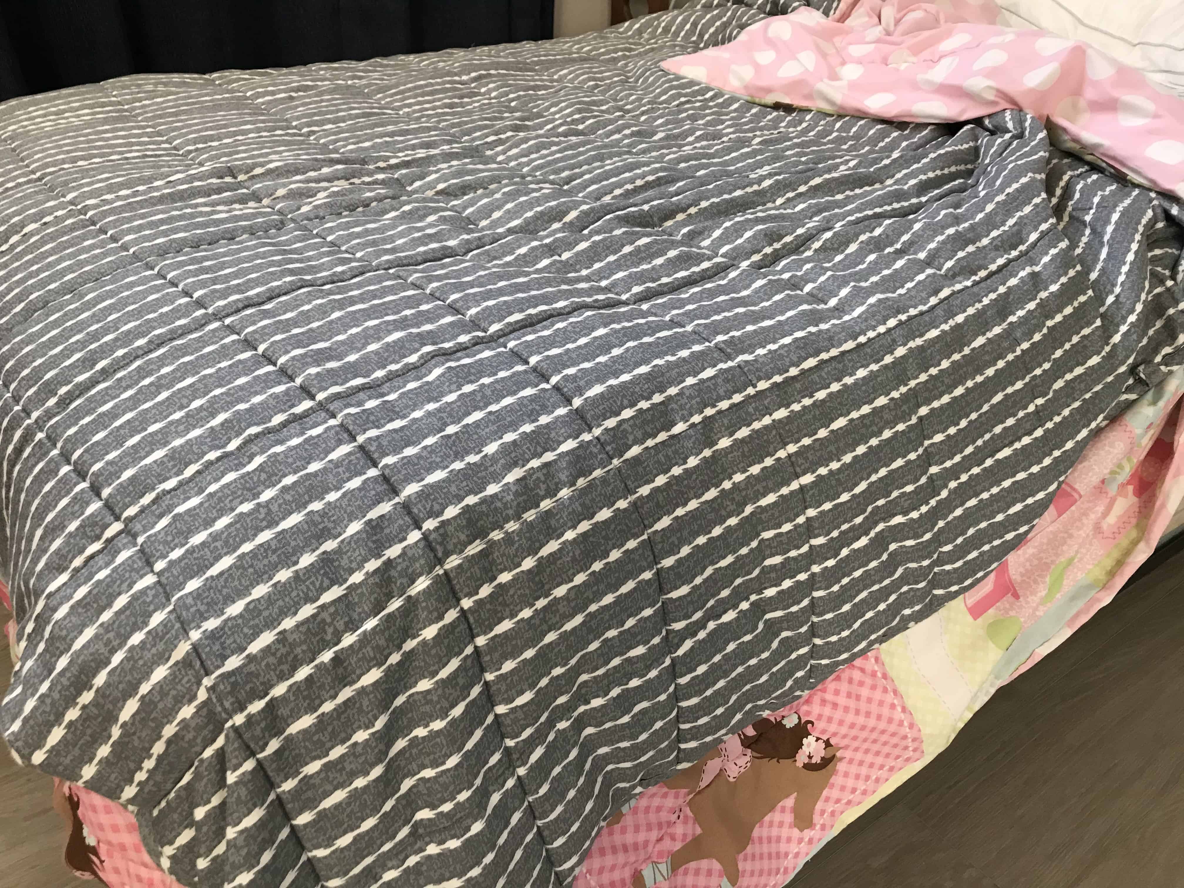 gray blanket on top of pink comforter