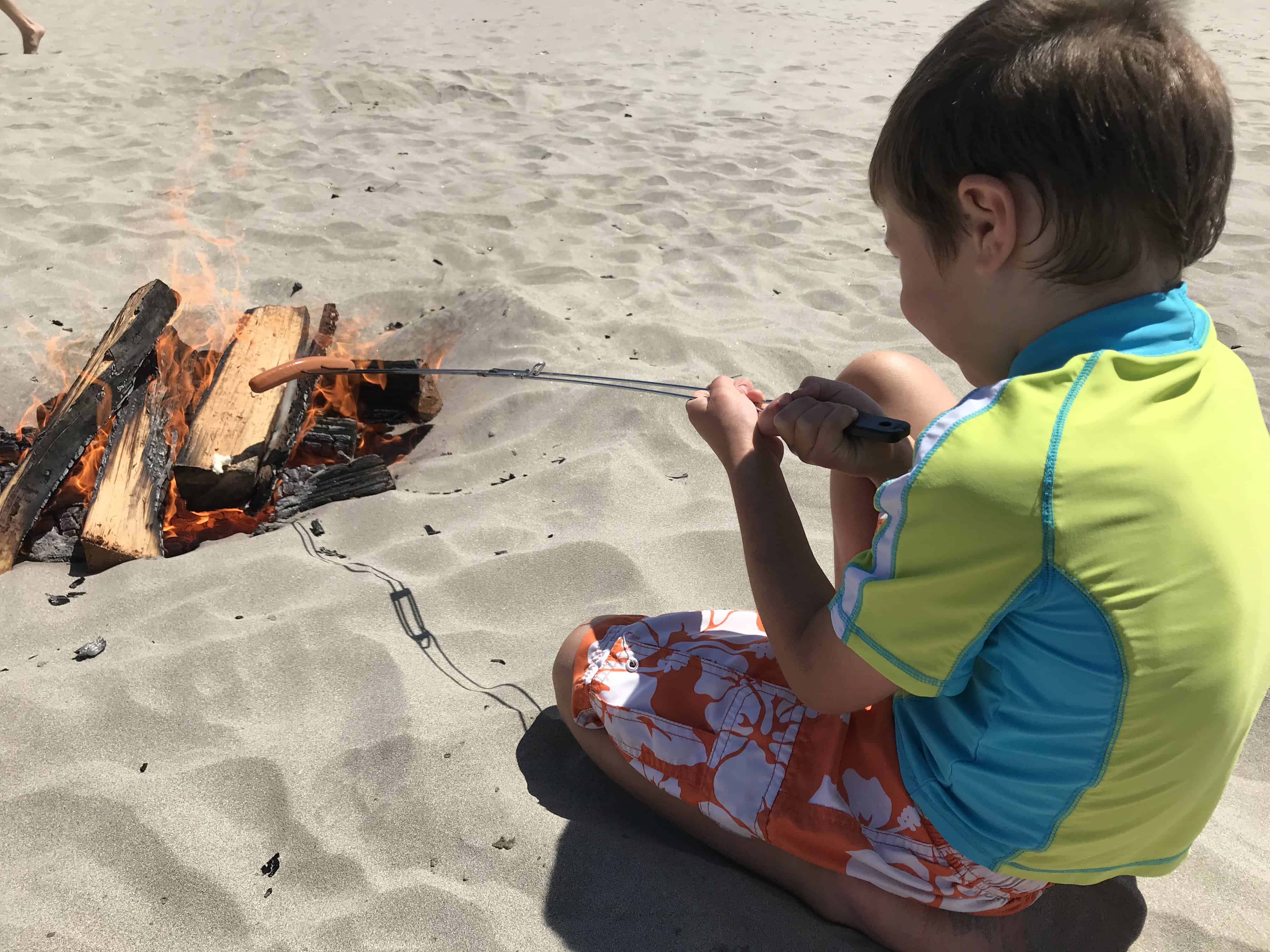 boy on sand with campfire