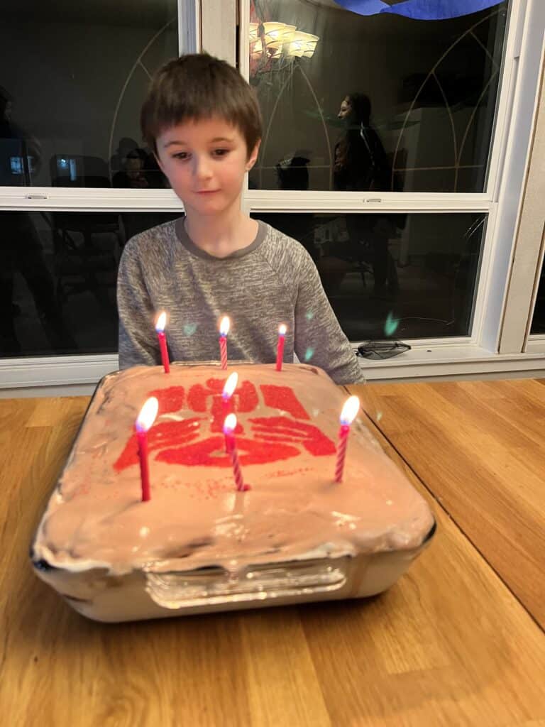 Our son looks at his birthday cake with candles lit.