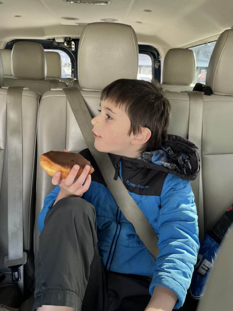 Our son finishes a donut inside our van.