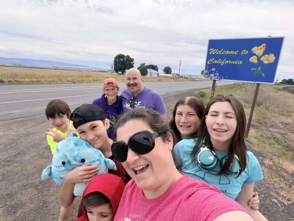 Our family on a recent road trip to California, standing in front of the Welcome to California sign.