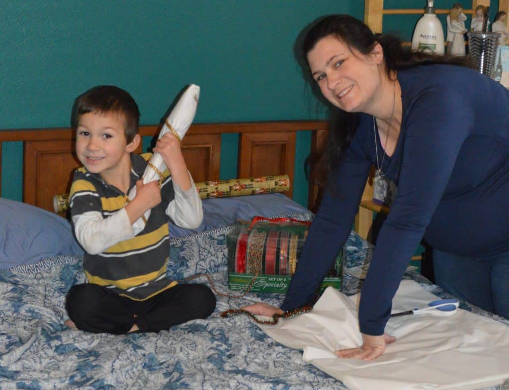 Mom and child wrapping gift. Part of Christmas gift planning includes planning to get everything wrapped.