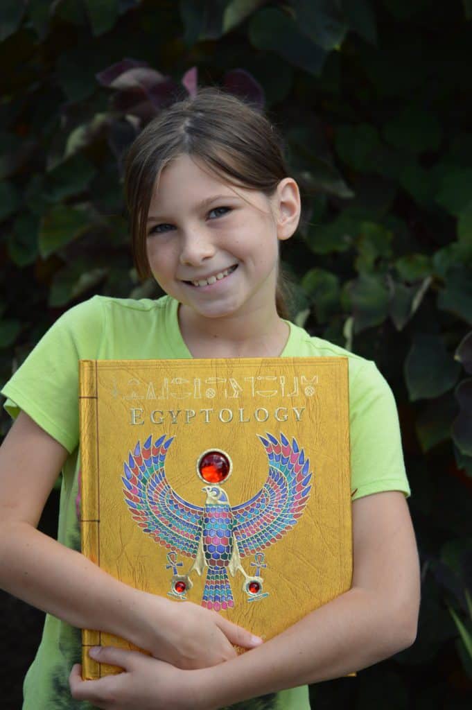 Girl holding Egyptology book. Back to School Homeschool Ideas.