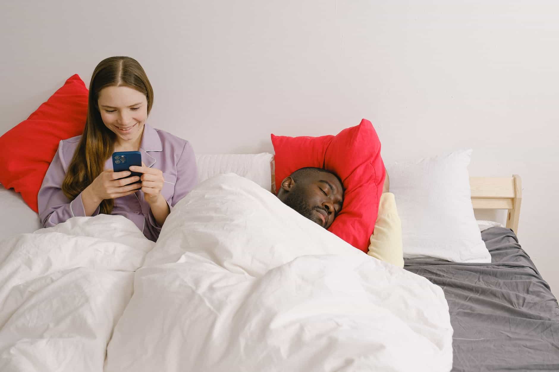 woman using phone beside the sleeping man