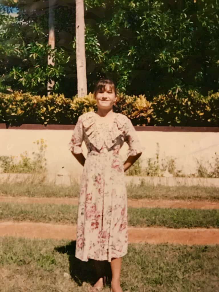 Teen in 90s dress in front of wall in Jamaica.