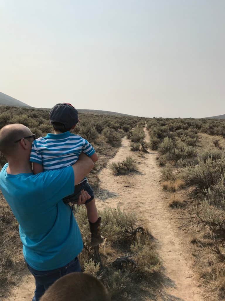 I hold up my son to give him a good look at the trail ruts at Flagstaff Hill in Eastern Oregon.