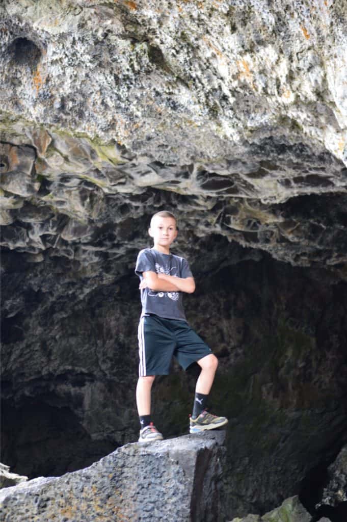 Boy in shoes on boulder in lava tube. craters of the moon Idaho with kids