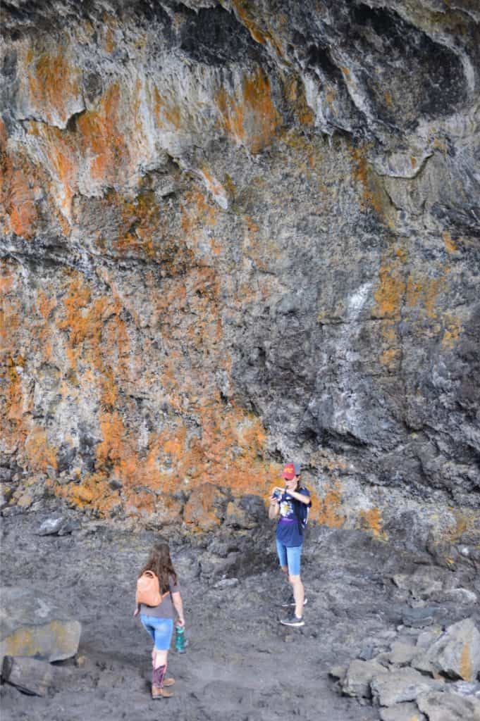 Orange lichen-covered rock face with girls in foreground. craters of the moon Idaho with kids