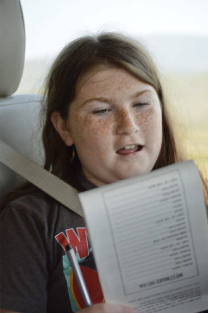 Girl reading from Mad libs book in van