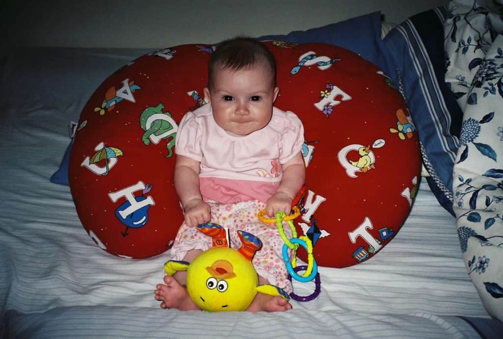 Baby sitting up with Boppy pillow and toys. Best baby registry ideas