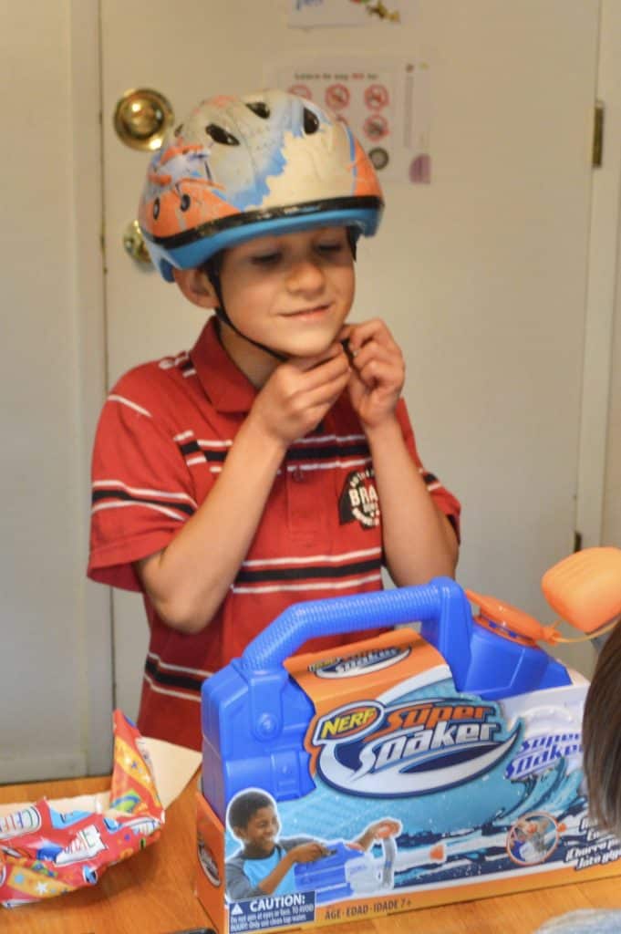 boy in helmet with super soaker gun in front of him