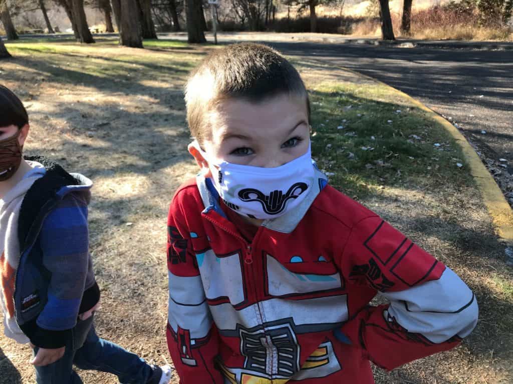 Scowling boy with transformer hoodie and storm trooper face mask. Grief during the holidays has been exacerbated by the difficult pandemic.