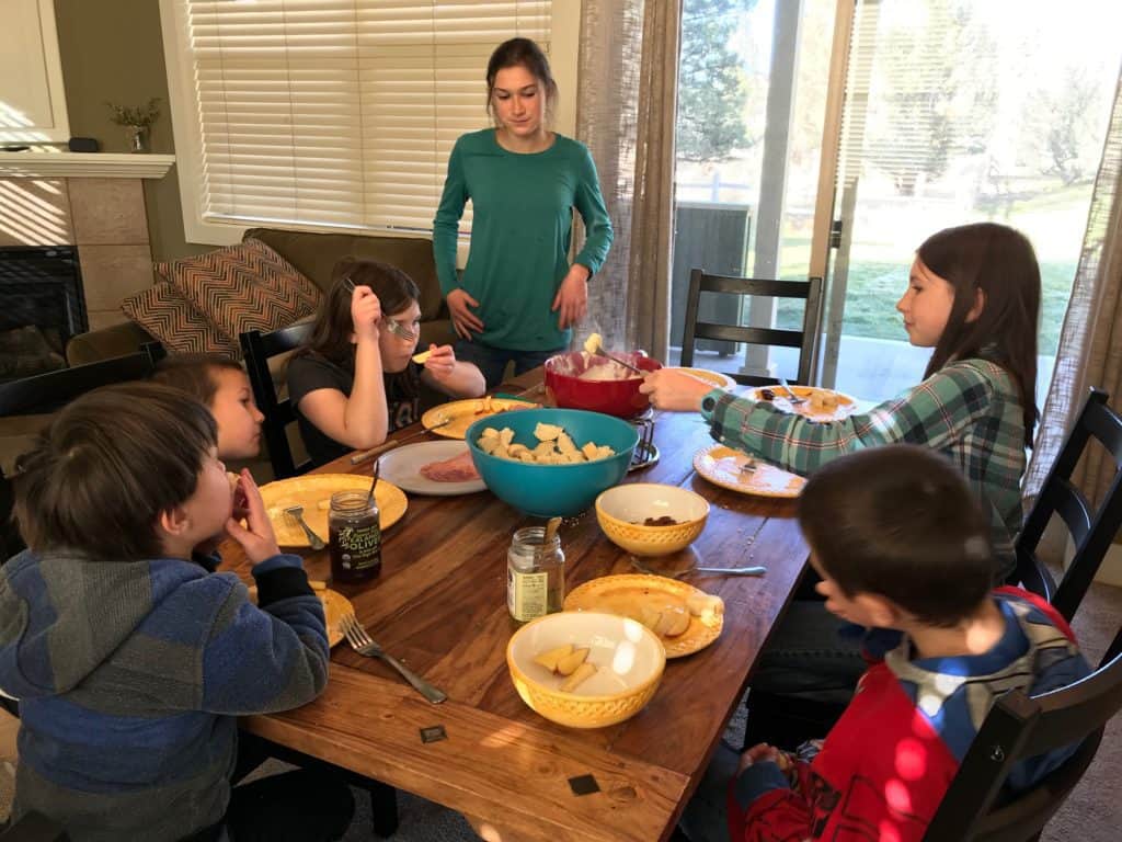 Kids at table eating cheese fondue. Simple meals that don't require a lot of prep are helpful when your family is experiencing grief during the holidays.