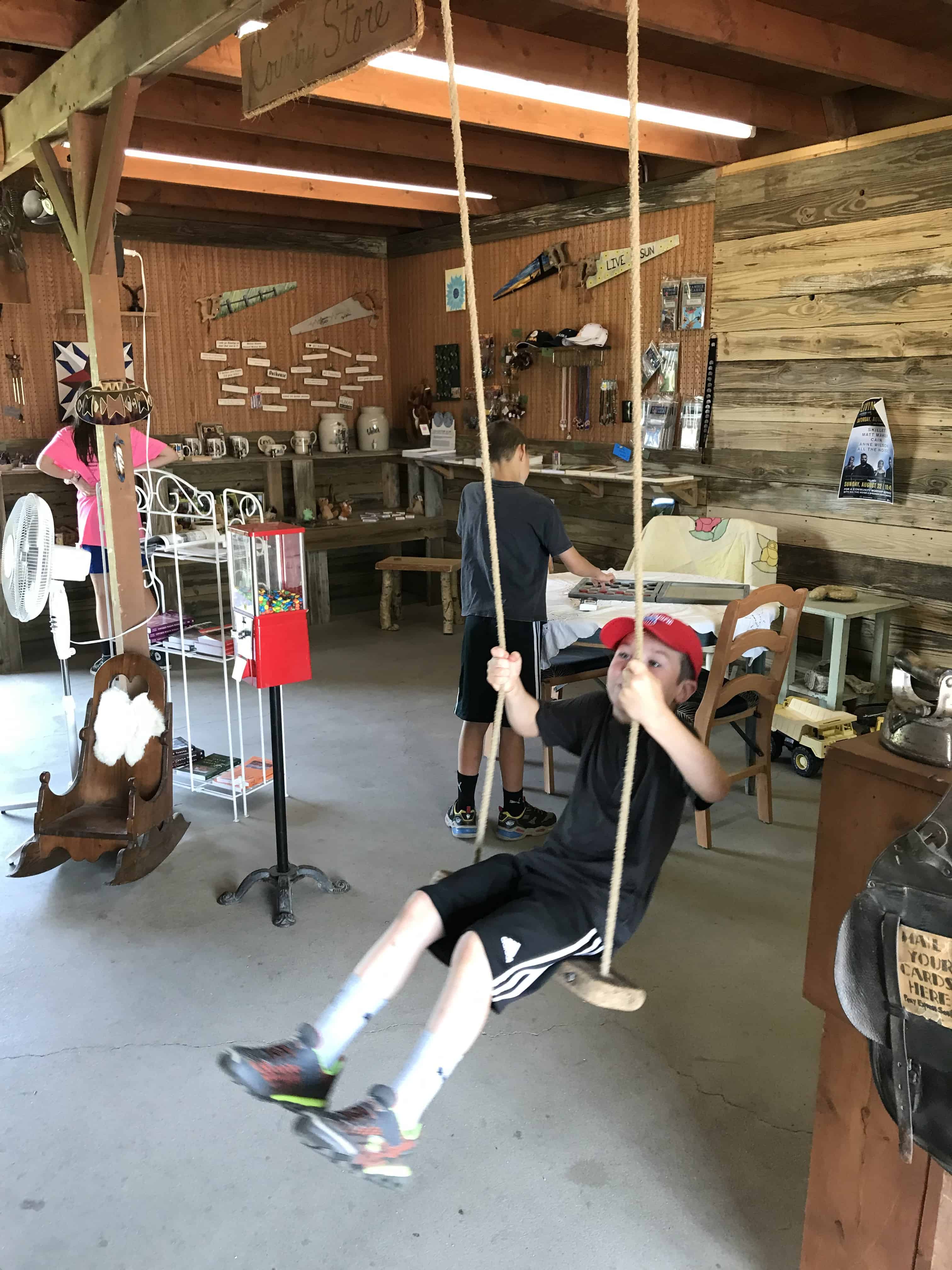 Boy on wooden swing inside store at the Sod house Museum