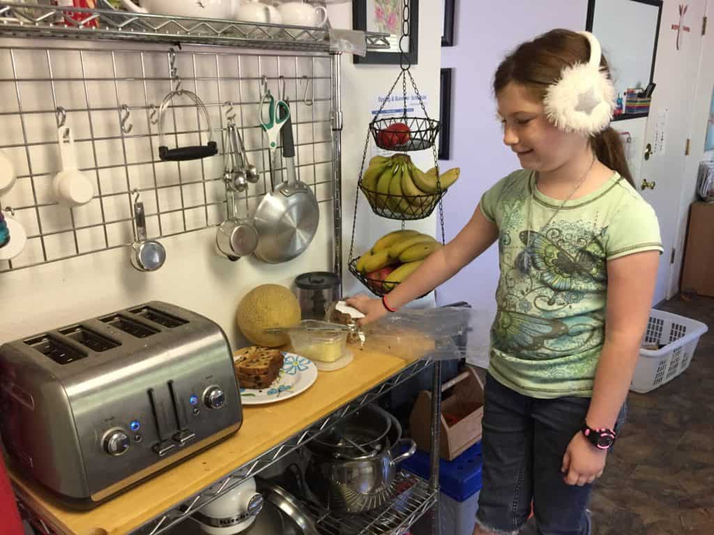 child with ear muffs making toast