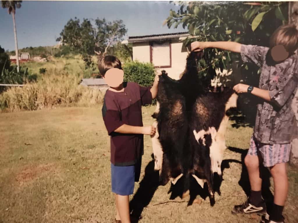 boys holding up black and white goat skin