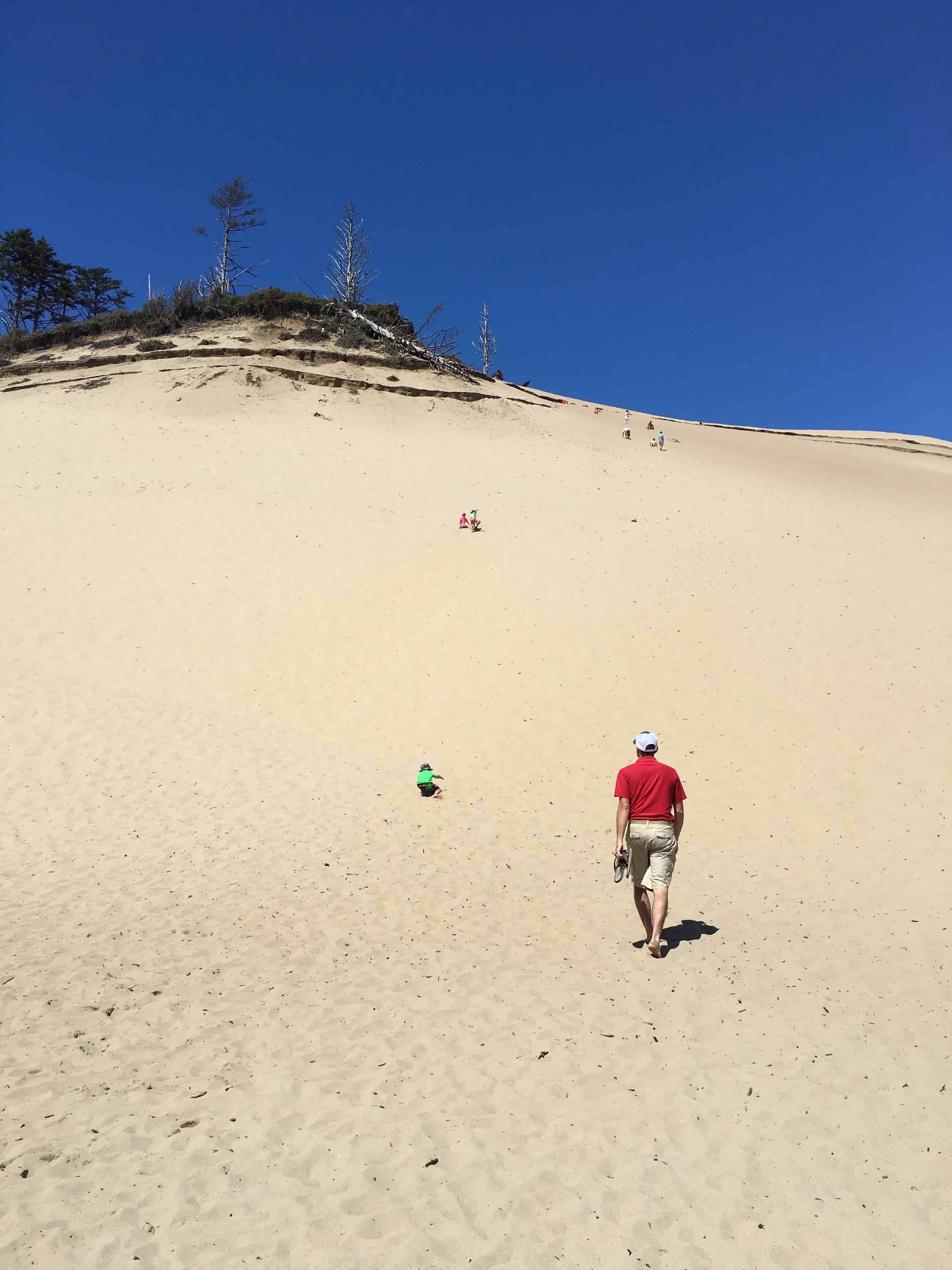 man in red shirt at bottom of sand dune