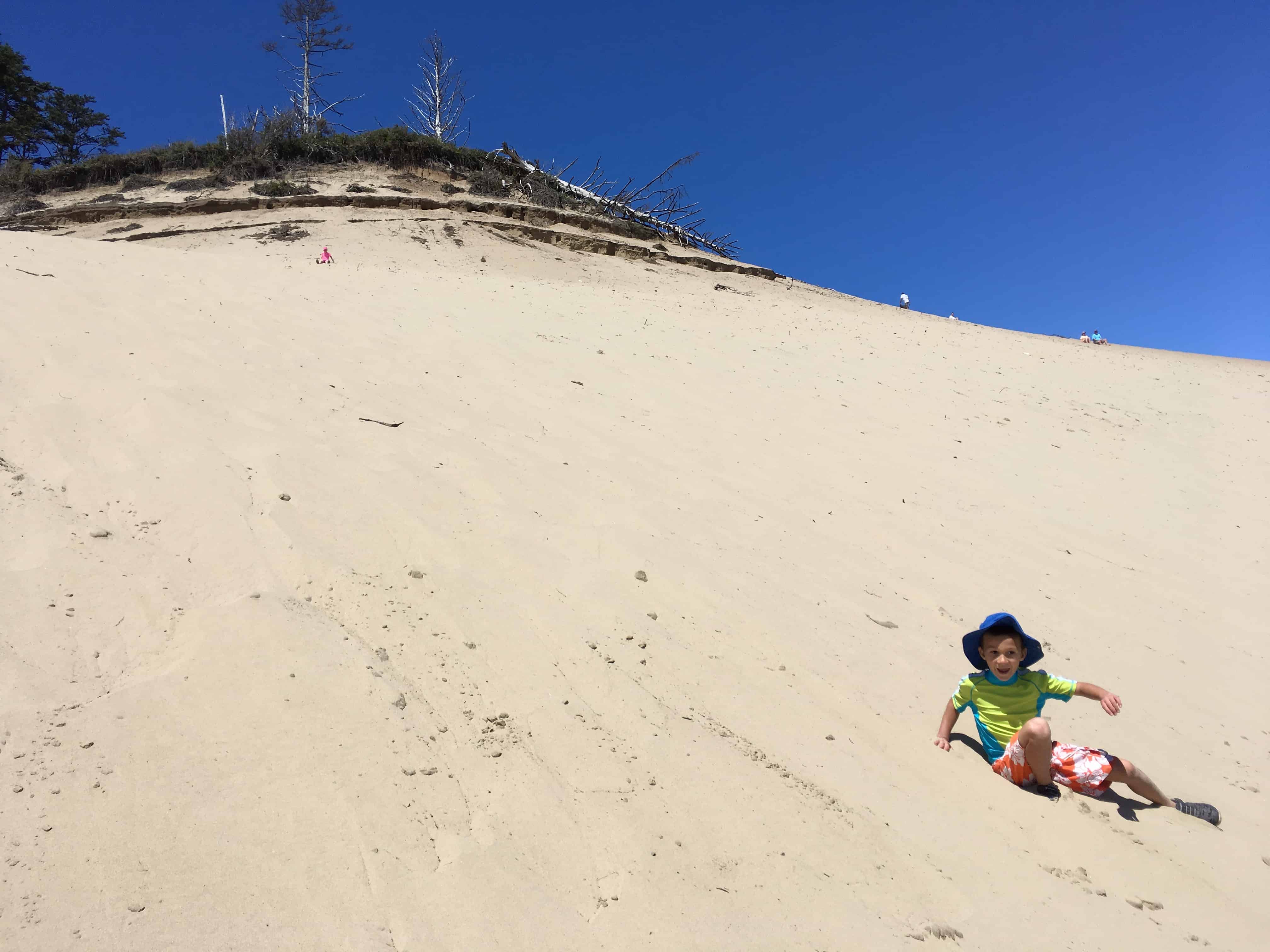 Kid climbing sand dune. The dune is a fun thing to do in Pacific City oregon with kids.