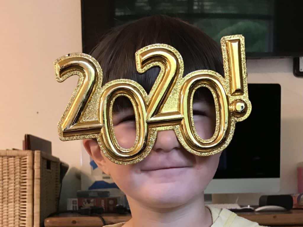 boy wearing gold glittery glasses frames that show "2020!"