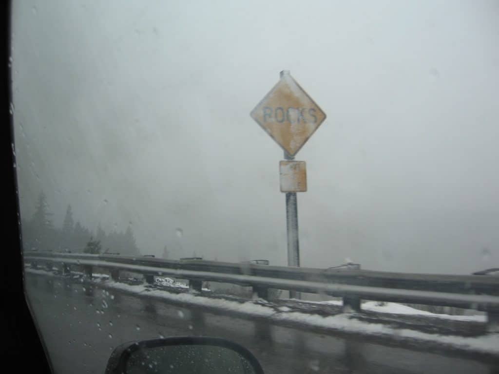 Snow covered roadside sign from car window. road trip packing list printable