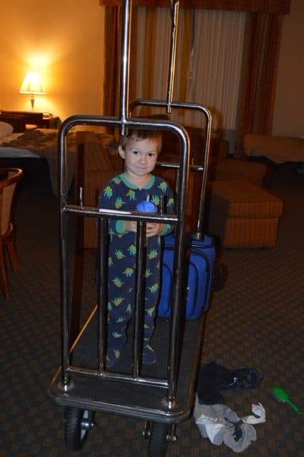 A child on a luggage trolley in a hotel. Check out our road trip packing list printable for great planning tips! 