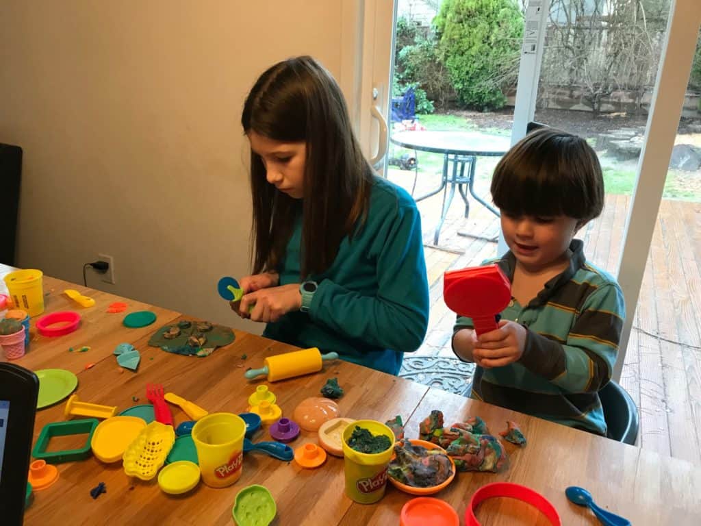 Girl and boy playing with Play-doh. Play-doh is one of our favorite easy activities to do with kids.