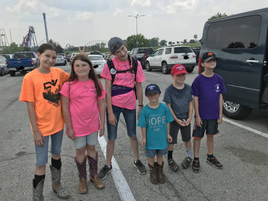 Six kids in bright shirts in a parking lot. Bright, matching shirts help parents find kids fast in crowded locales.