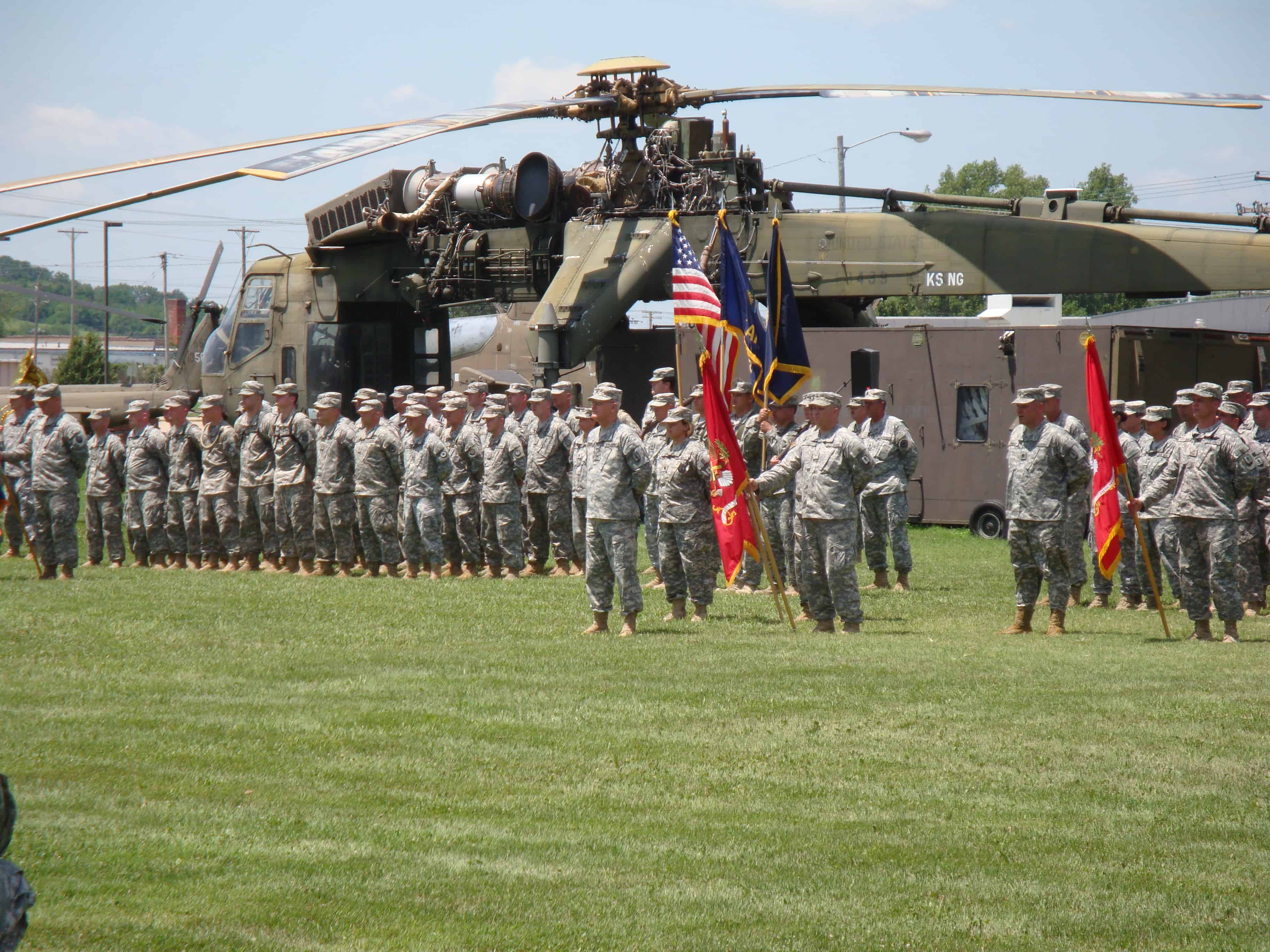 Soldiers stand at attention on the grounds of the Museum of the Kansas National Guard. Behind them sits an enormous transport helicopter.