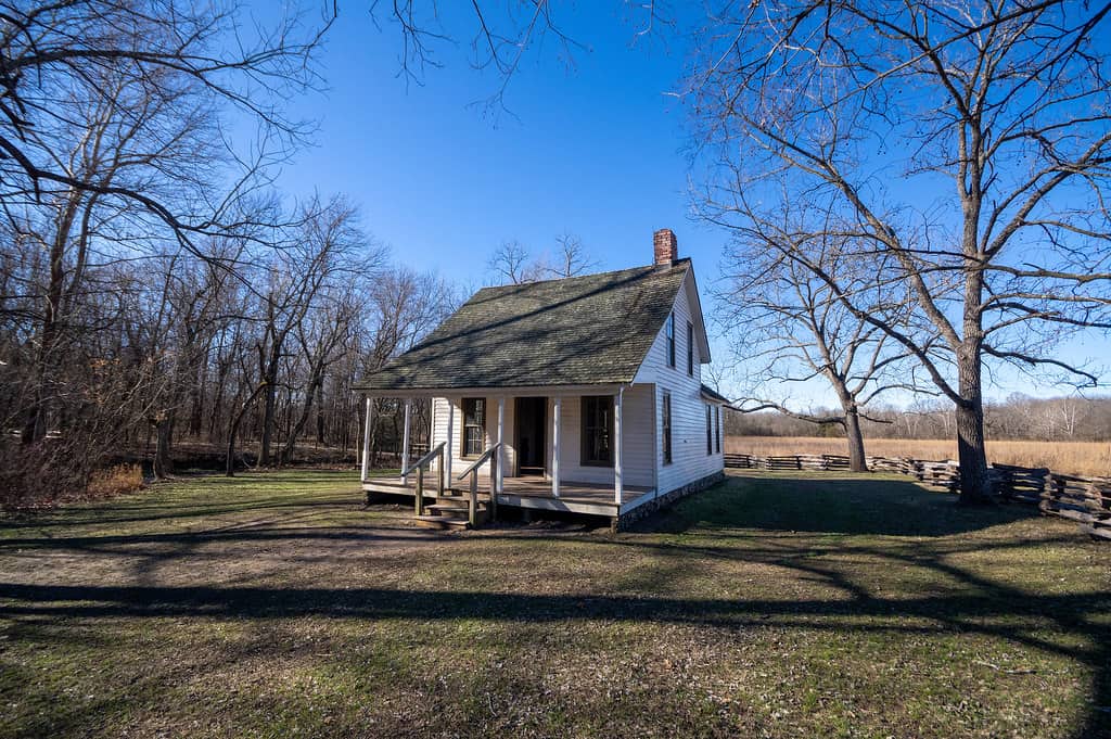 A small farmhouse stands among trees and farmland at George Washington Carver National Monument. 