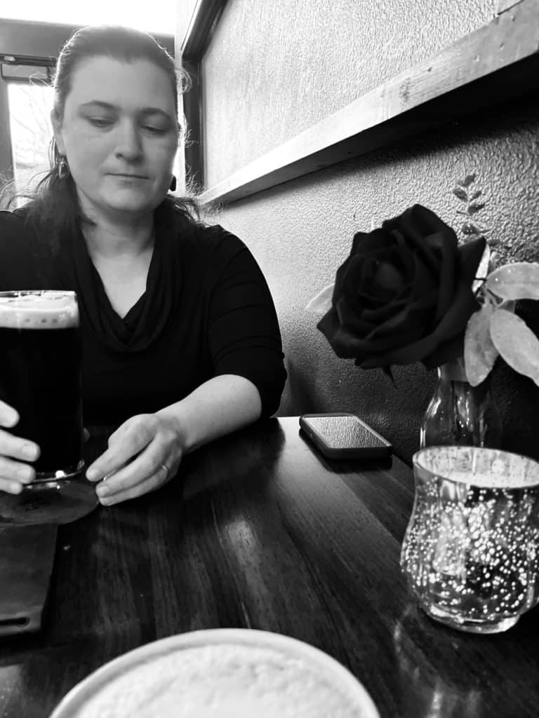 Woman holding glass at a table in the Noble Fox.