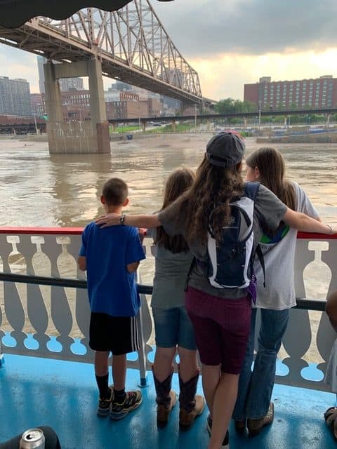 Kids on steamboat deck sailing the Mississippi River. The steamboat cruise leaves from right below the Gateway Arch National Park in St. Louis, MO
