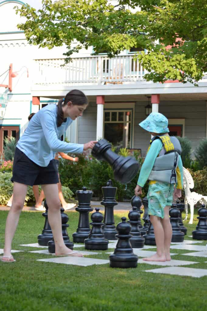 Our oldest daughter teaches her youngest brother how to play chess with a giant lawn chess set