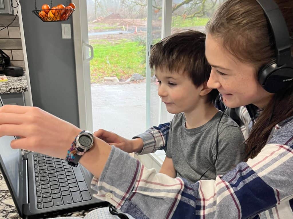 Girl and little boy looking at computer together.