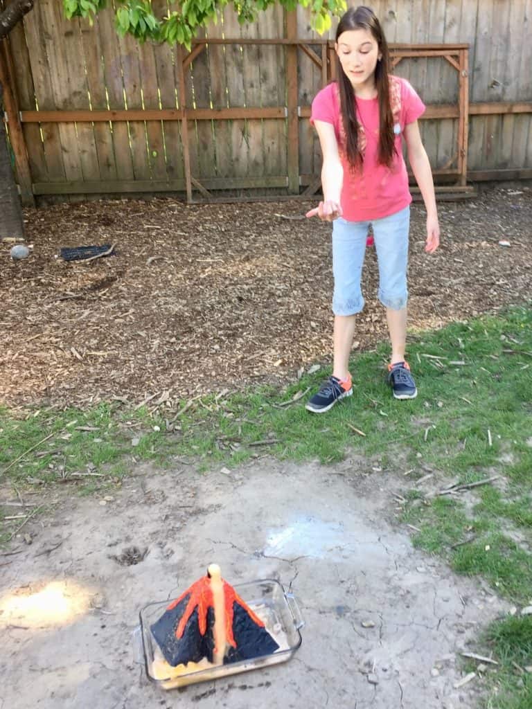 Girl with volcano experiment in yard.