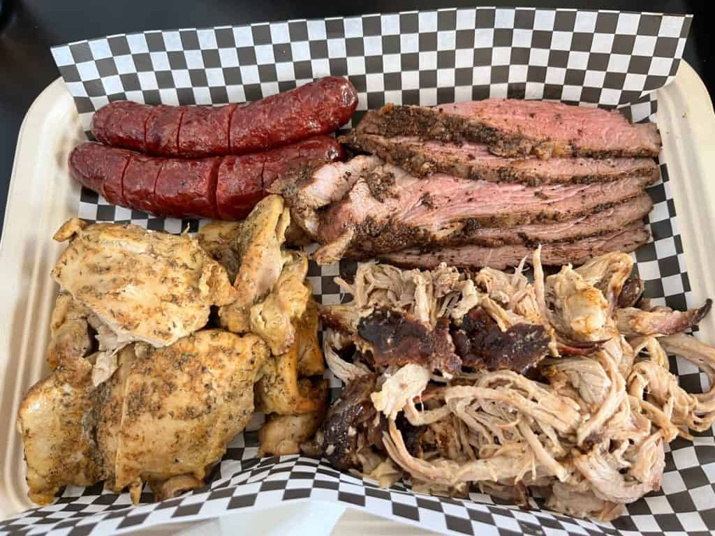 Fat head BBQ's family meat platter showing chicken, sausage, brisket and pulled pork.