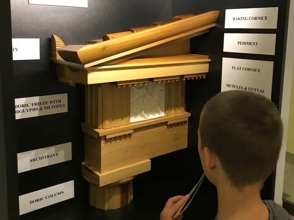 Display showing architectural features of the Nashville Parthenon, with boy studying the display.