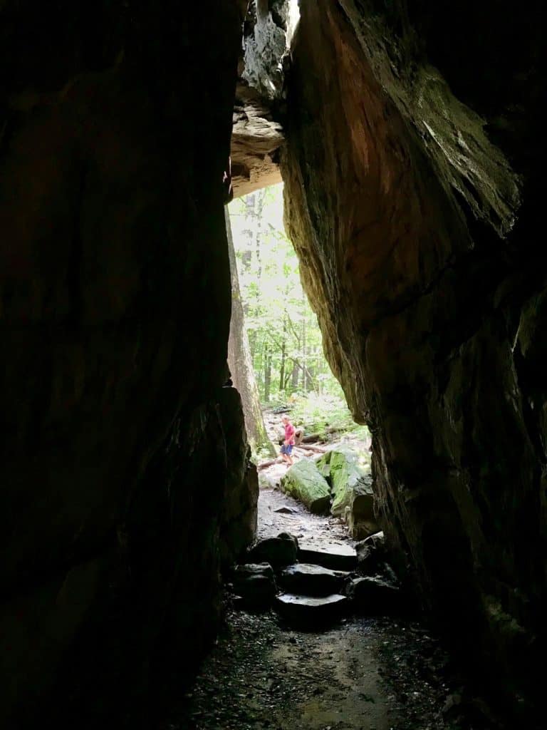 Rock crevice with child running in distance.