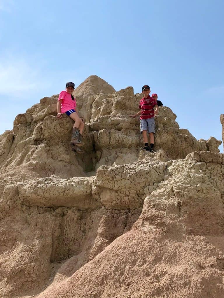 Kids climbing rock formations at Badlands NP.