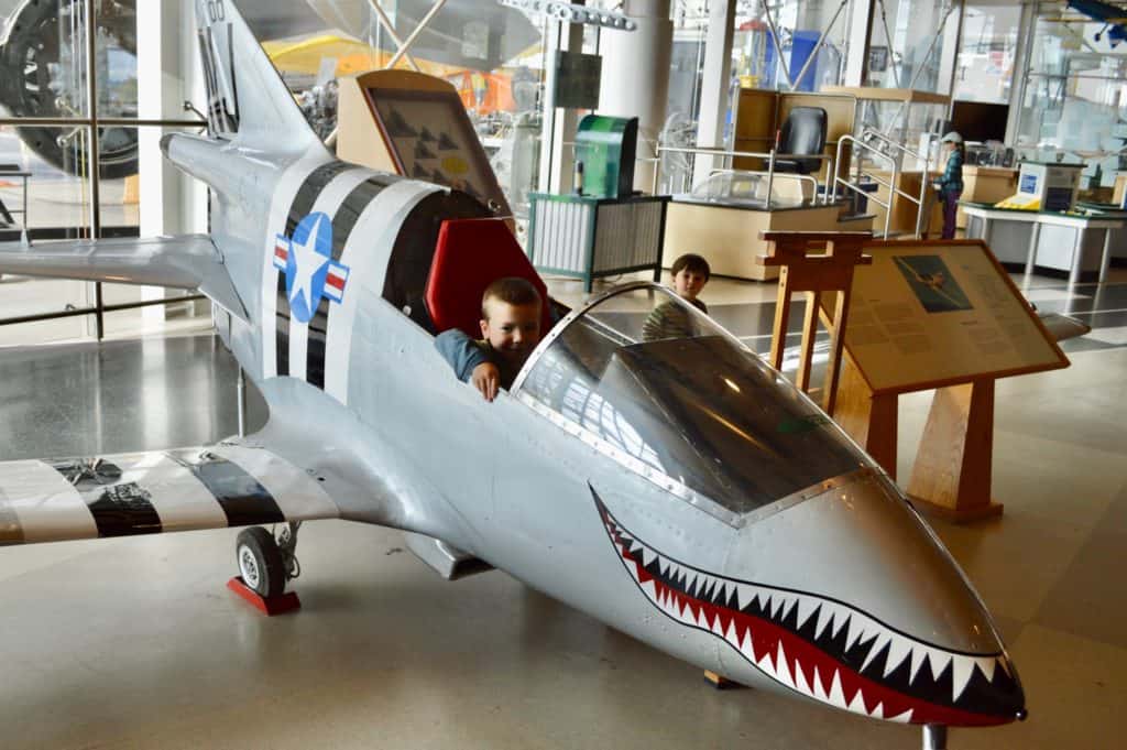 Boy in cockpit of model fighter jet