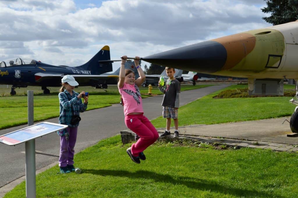 Girl hanging off nose of fighter jet. The Evergreen Aviation Museum is one of the favorite things to do in McMinnville with kids.