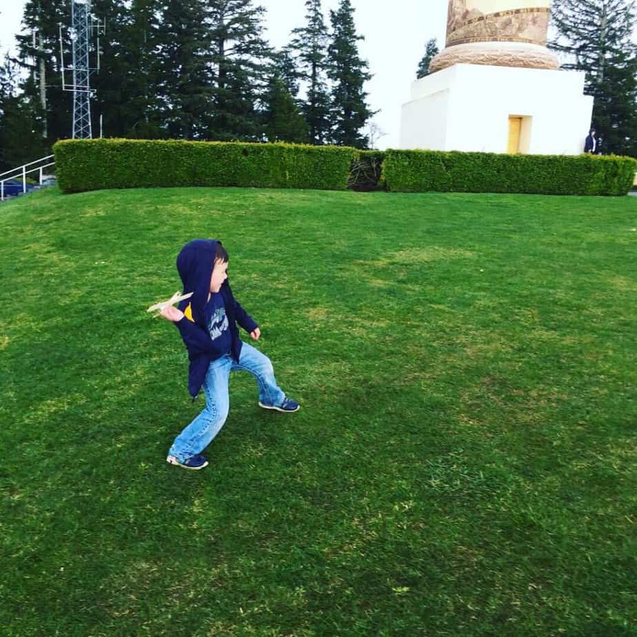 Boy preparing to throw a wooden glider at the base of the Astoria Column.