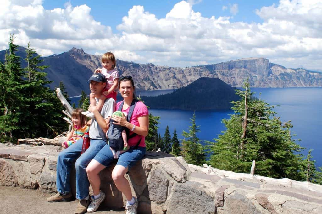 Family on ledge in front of Crater Lake, the most well known of the Oregon National Parks.