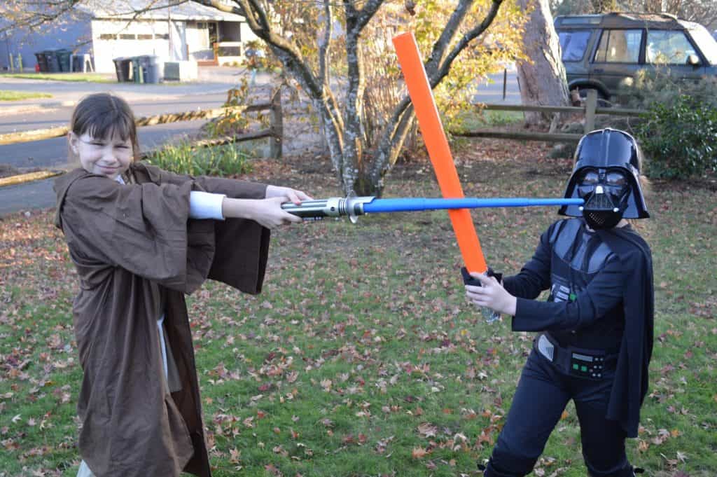 Girl and boy in Star Wars costumes having a lightsaber battle. Who to talk to about ADHD.