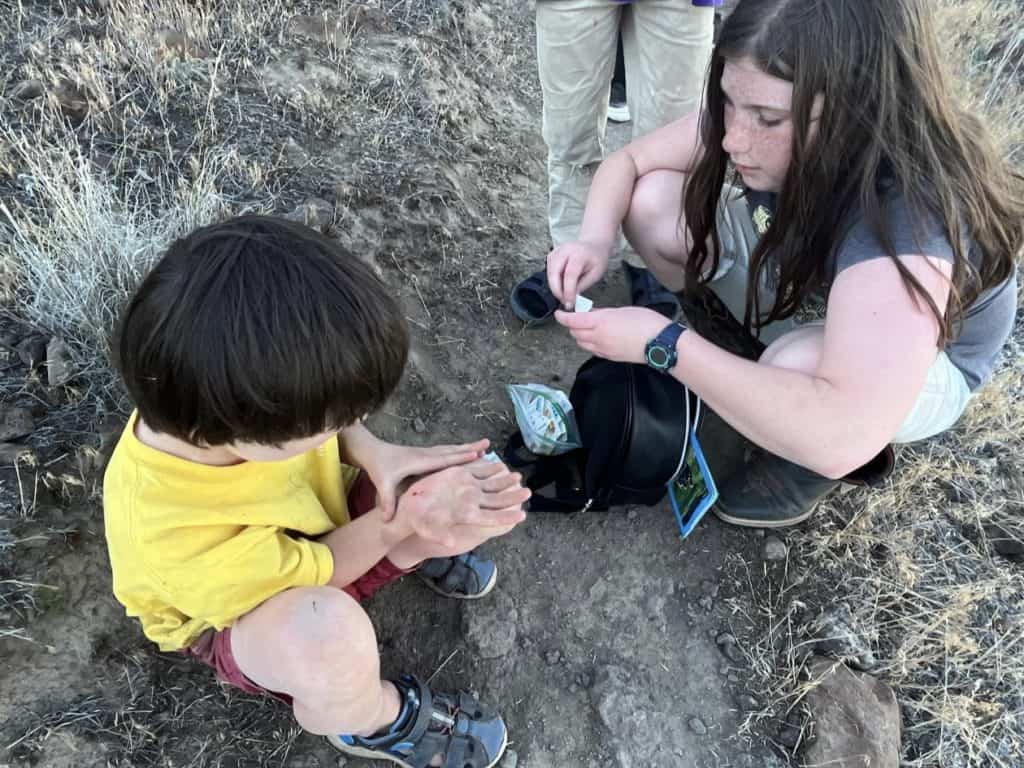 Girl giving boy a bandaid. A first aid kit is a must when camping with your kids.