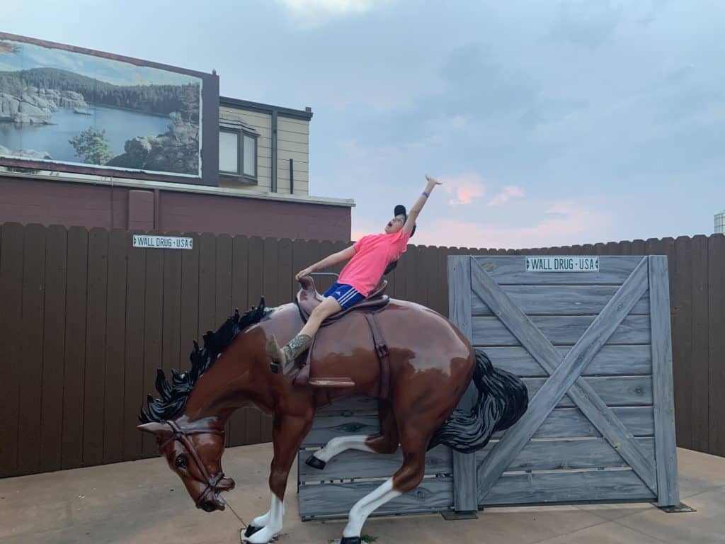 Girl pretending to be riding a real bucking bronco.