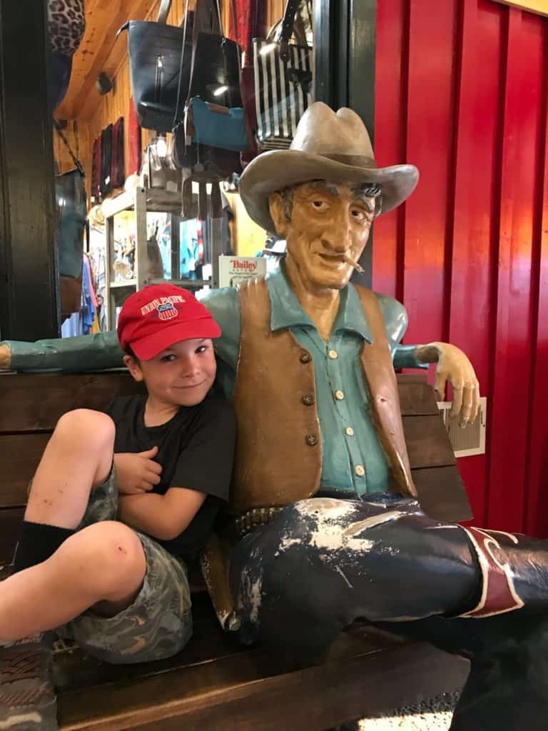 Boy next to old wooden cowboy at Wall Drug, one of the restaurants in Badlands National Park.