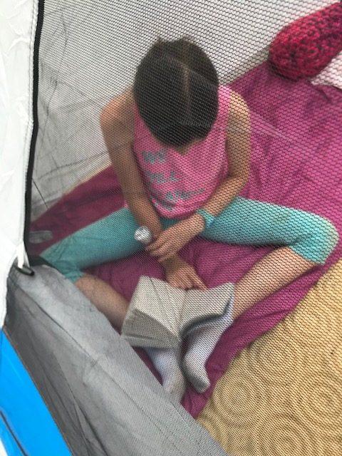 Reading in the tent is a good rainy day option. Camping ideas for families.