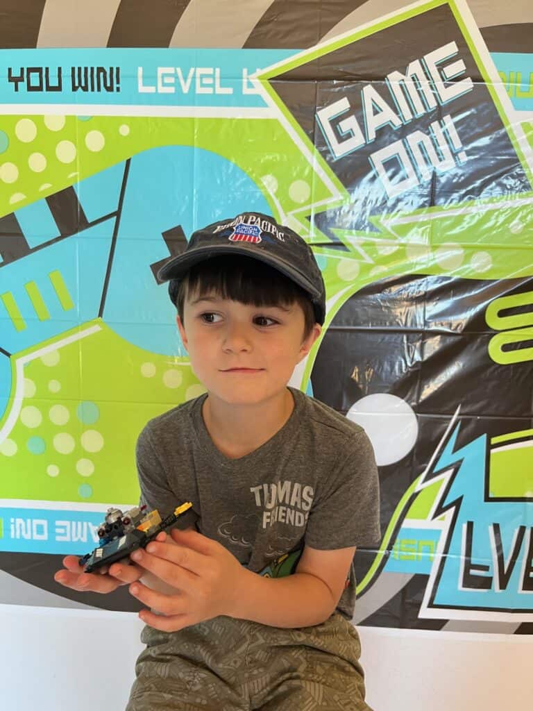 Our youngest son in front of a video game theme poster that says "Game One!"