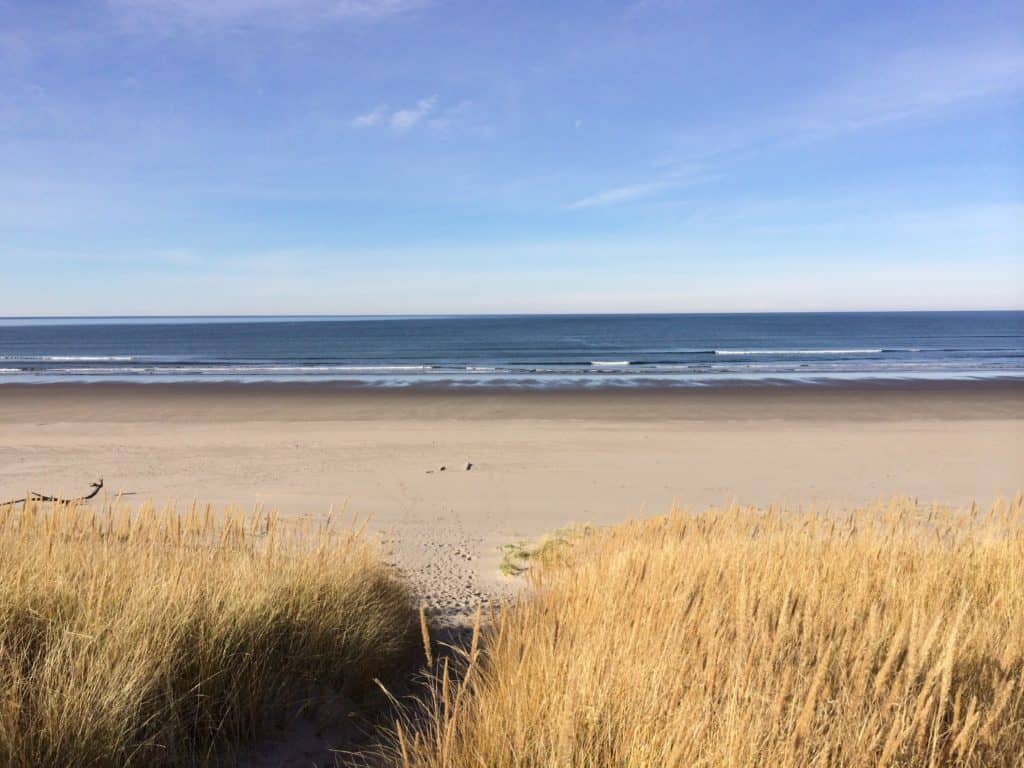 Ocean waves lap up against an empty beach at Sunset Beach State Recreation Site. Sunset Beach is one of the 21 best beaches in Northern Oregon.